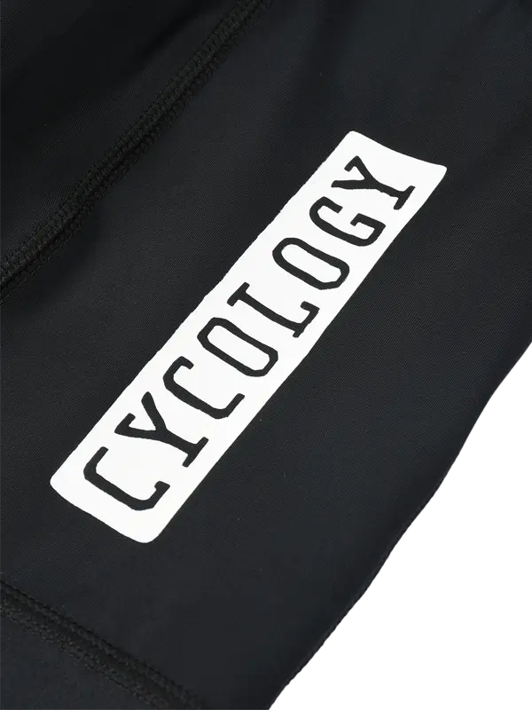 Close-up of a black garment featuring a white rectangular branding on the side cargo pocket with the word 'CYCOLOGY' printed in black.