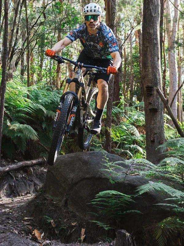 Man mountain biking through forest trail in cycling jersey and helmet