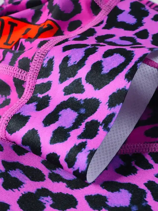Vibrant pink and purple leopard print cycling shorts with padded chamois and orange logo detail