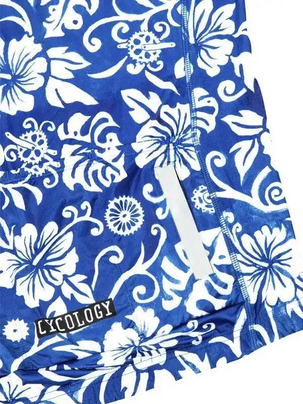 Blue cycling jersey with white floral and gear pattern, featuring reflective strip and brand tag