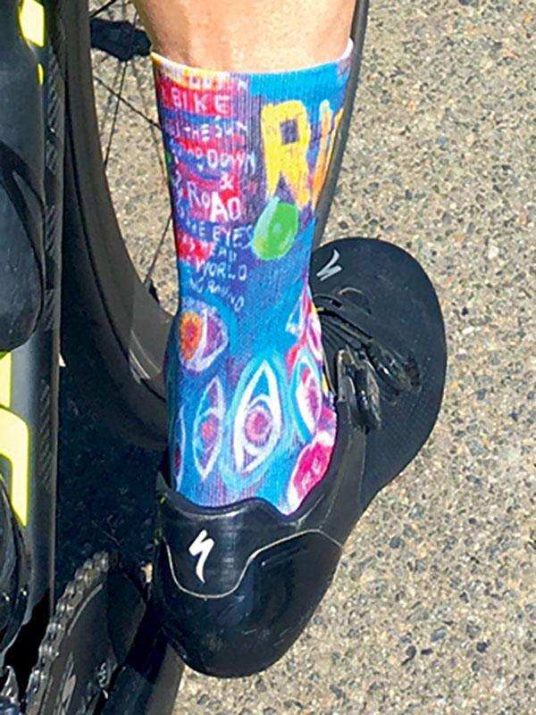 Colorful cycling socks with bold graphics worn with black bike shoes on pavement