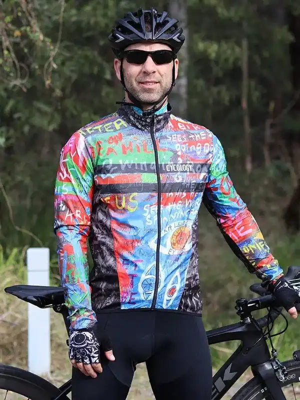 Man in colorful graphic cycling jersey and helmet, standing with road bike outdoors