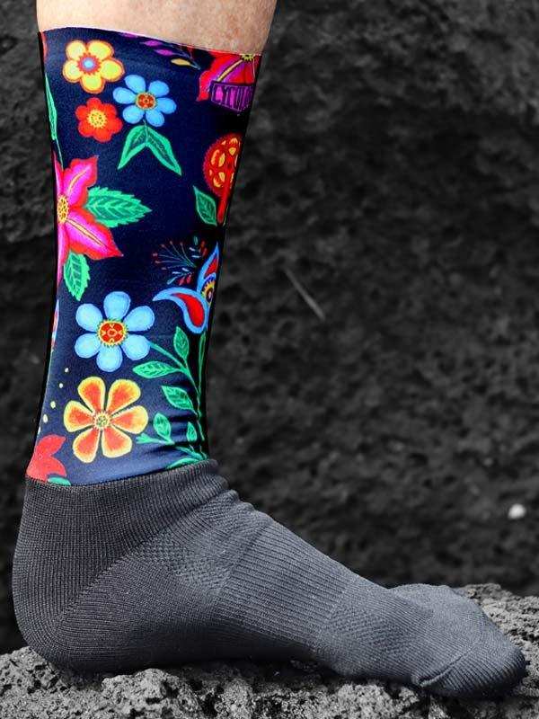 Colorful floral cycling socks with vibrant flowers on dark background, worn on foot outdoors