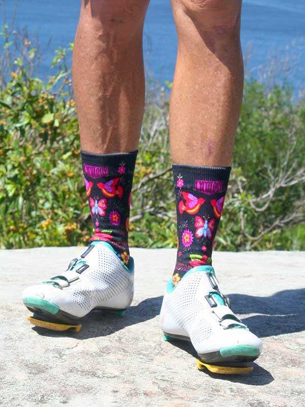 Colorful floral cycling socks with butterflies, worn with white bike shoes outdoors