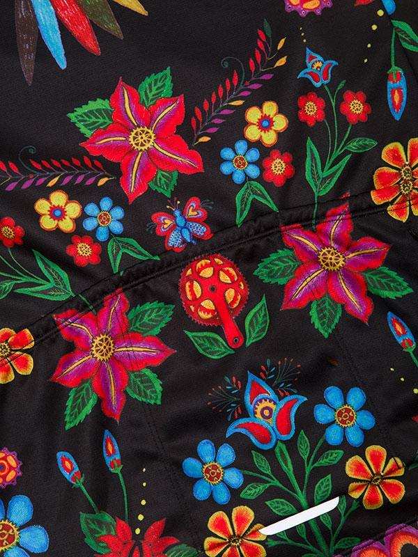 Vibrant floral and butterfly print on black cycling jersey fabric, featuring colorful flowers and green leaves.