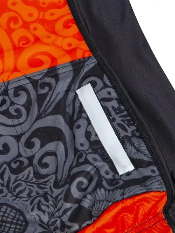 Men's cycling shorts with bold orange and gray swirl pattern, reflective strip, and ergonomic design