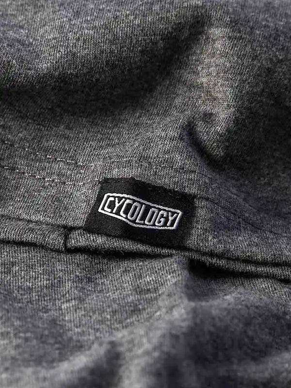 Cycology brand tag on dark grey cycling apparel fabric, showcasing quality stitching and design detail.