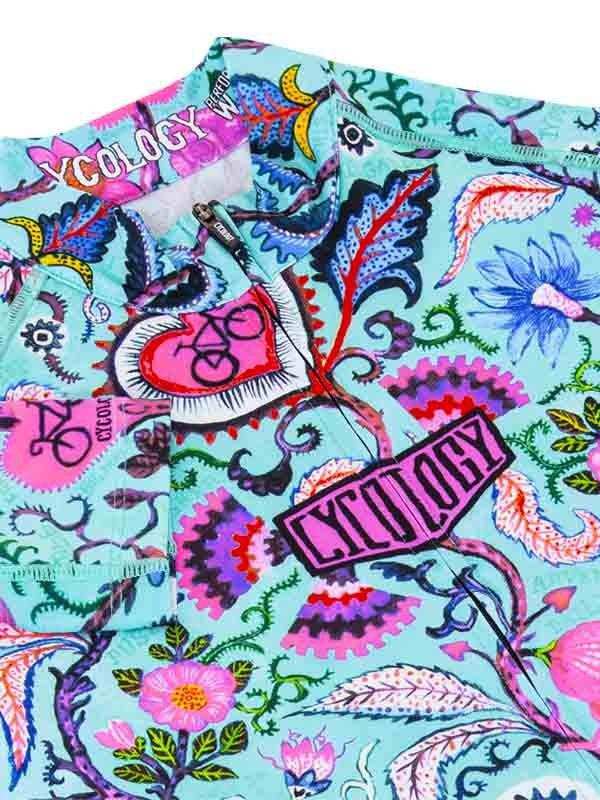 Vibrant floral and paisley cycling jersey with bold pink 'CYCOLOGY' logo and bike graphic on turquoise fabric.