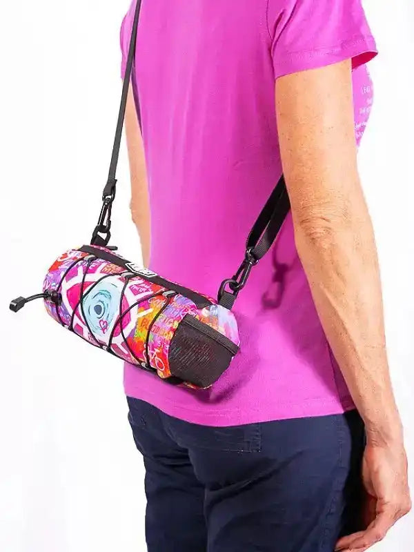 Colorful cycling frame bag with vibrant pattern, worn crossbody by person in pink shirt
