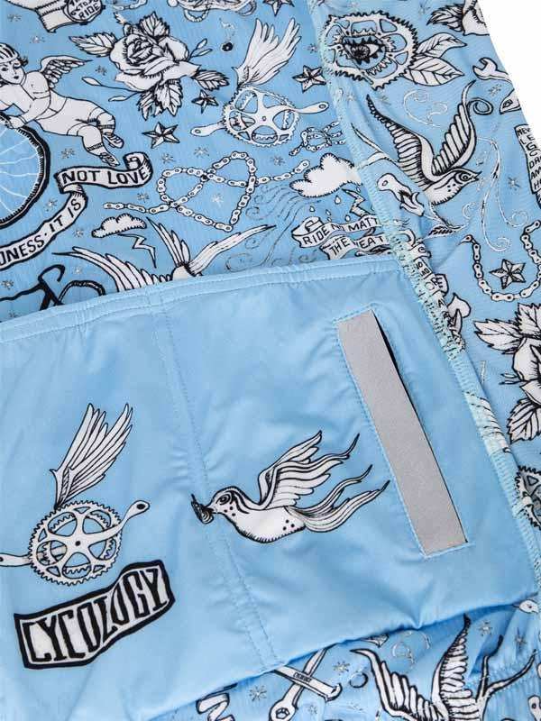 Light blue cycling shorts with tattoo-style bird, rose, and gear print, featuring reflective strip and pocket