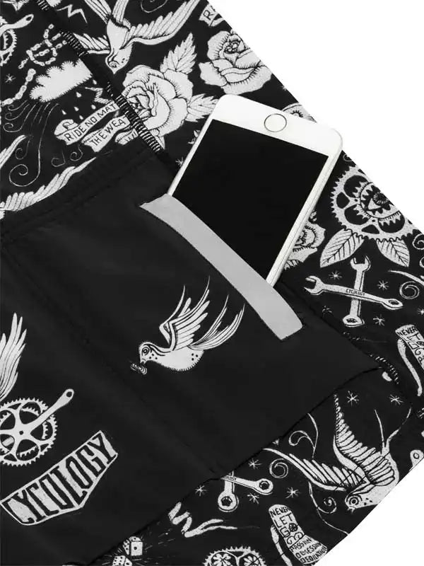 Black cycling shorts with white tattoo-style graphics, featuring birds, roses, and tools, with phone in pocket