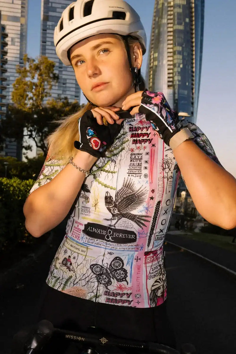 Woman in colorful graphic cycling jersey and helmet, urban skyline background, ready to ride.