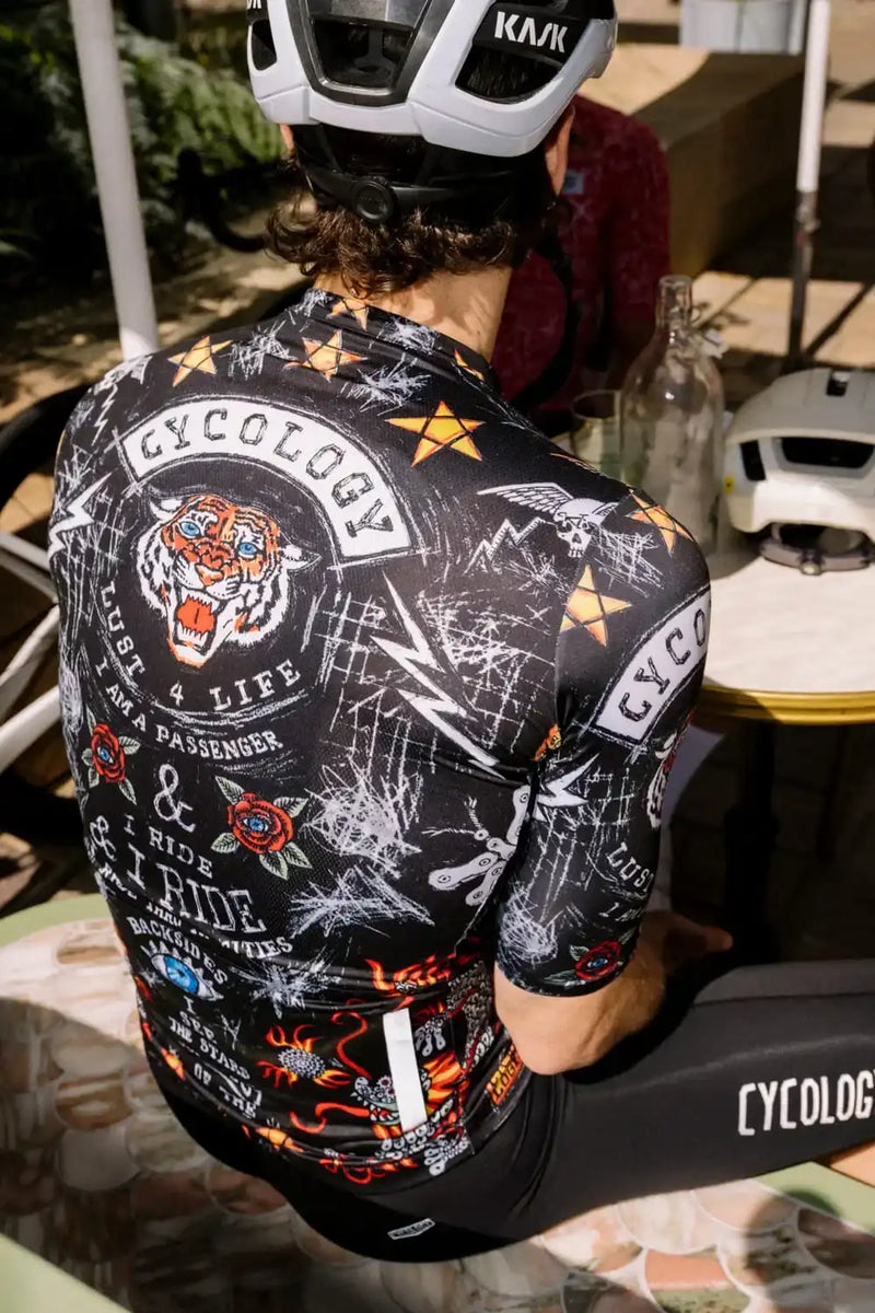 Men's cycling jersey with bold tiger graphic, stars, and 'Cycology' branding, worn with helmet and bib shorts.