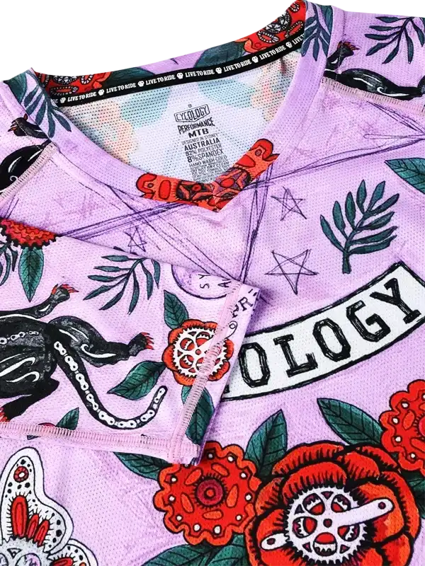 Purple women's cycling jersey with floral and tattoo-style graphics, featuring bold red flowers and green leaves