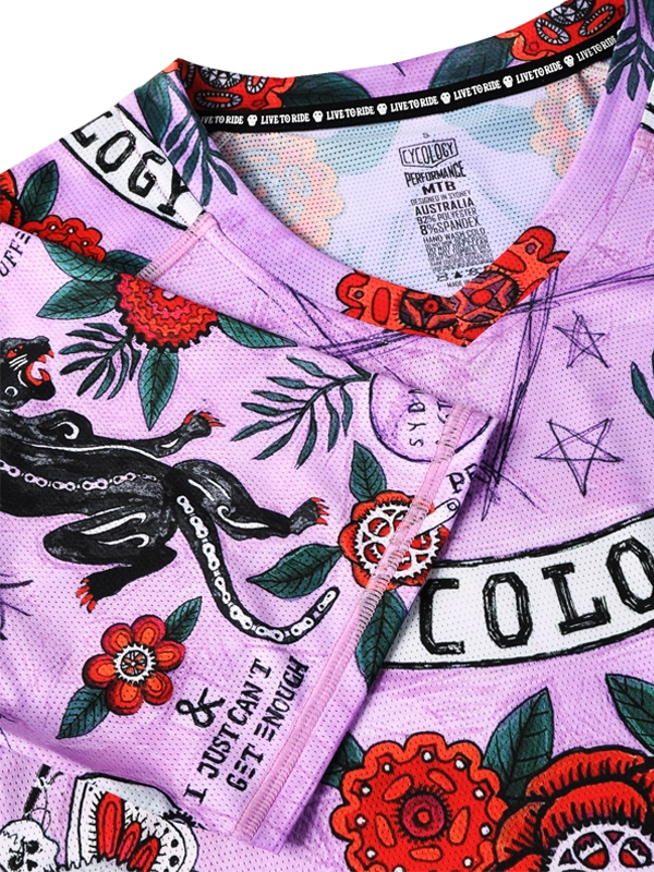 Close-up of a purple MTB cycling jersey with colorful designs and brand logos.