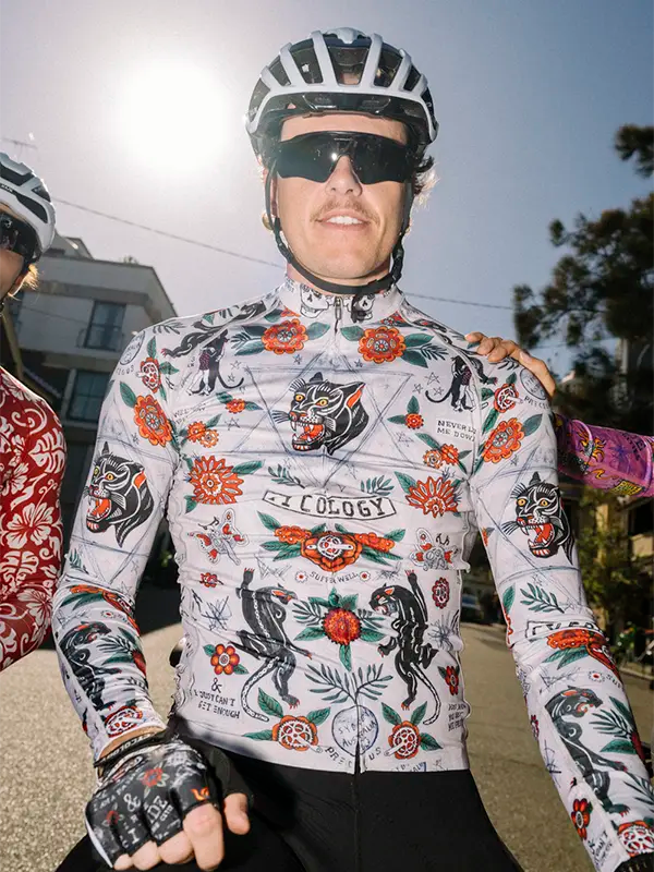 Cyclist wearing a  Long-sleeve cycling jersey with floral and panther design on a grey background