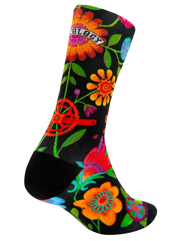 A single crew cycling sock with a black background and a vibrant, colorful floral and gear pattern. The word 'CYCOLOGY' is printed across the upper portion in a retro font.