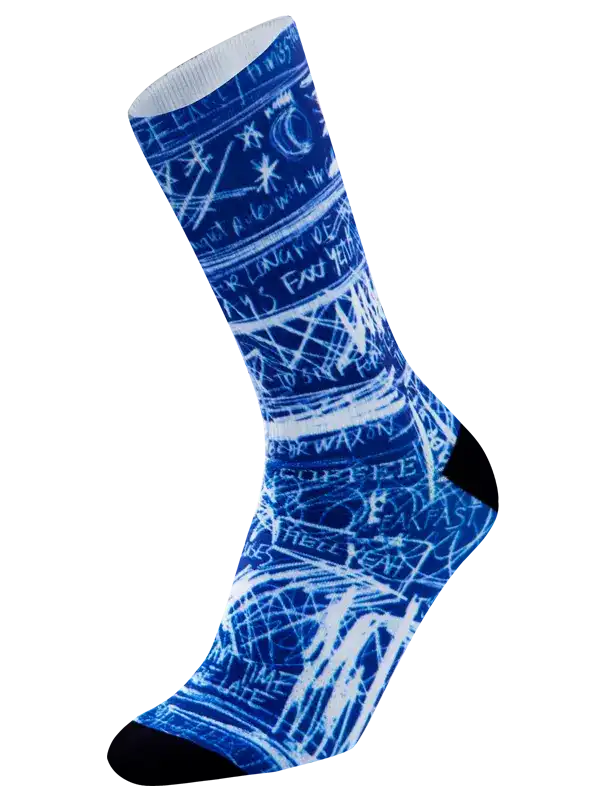A single crew-length cycling  sock featuring a blue and white abstract scribble pattern with white text-like markings, black heel and toe sections, and a white ribbed cuff, shown on a plain white background.