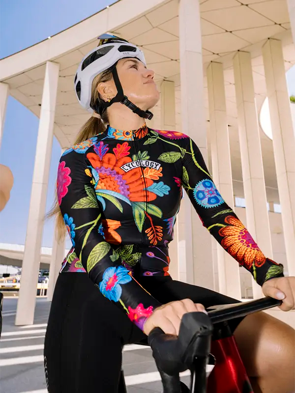 Cyclist wearing colorful floral-patterned long sleeve cycling jersey on a black background