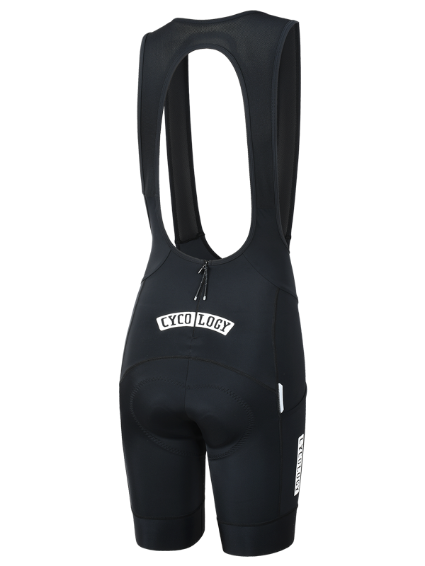 Black women's quick pee cycling bib shorts with a white 'CYCOLOGY' logo on the back waist below rear zipper shown from the rear on a white background.