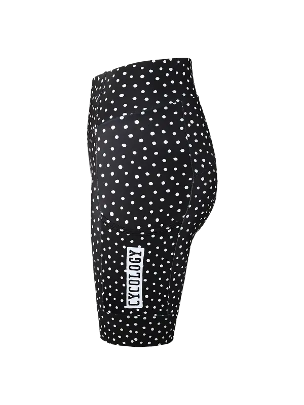 Black and white polka dot  cargo cycling shorts with a vertical white brand label reading 'CYOLOGY' on the lower left leg, shown from a side profile view  with a pocket against a plain white background.