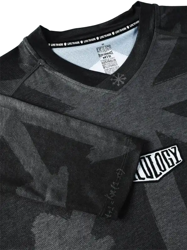 Men's black cycling jersey with geometric pattern, 'LIVE TO RIDE' neck tape, and brand patch detail
