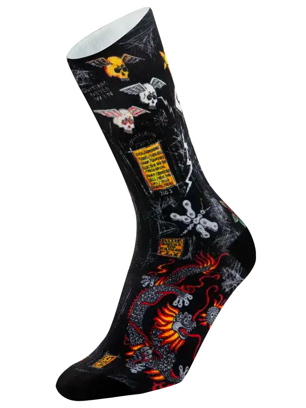 A single crew cycling sock with a black background and a complex graphic print featuring a red and orange dragon, white skulls, yellow warning-style labels, and spiderwebs.