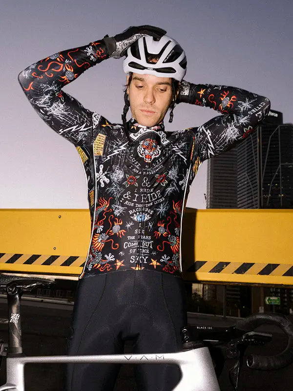 Person wearing a Black long sleeve cycling jersey with colorful graphics and 'Cycology' branding with a helmet, 