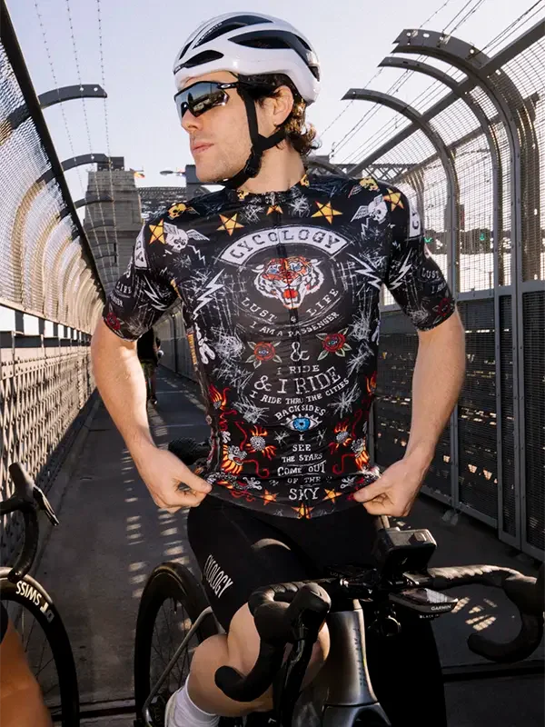 Cyclist wearing a black  patterned cycling jersey on a bridge