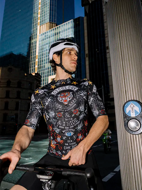 Person wearing a black colorful cycling jersey with a cityscape background 