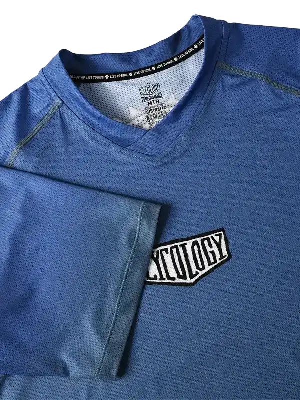 Blue men's cycling jersey with 'CYCOLOGY' chest patch and performance fabric details