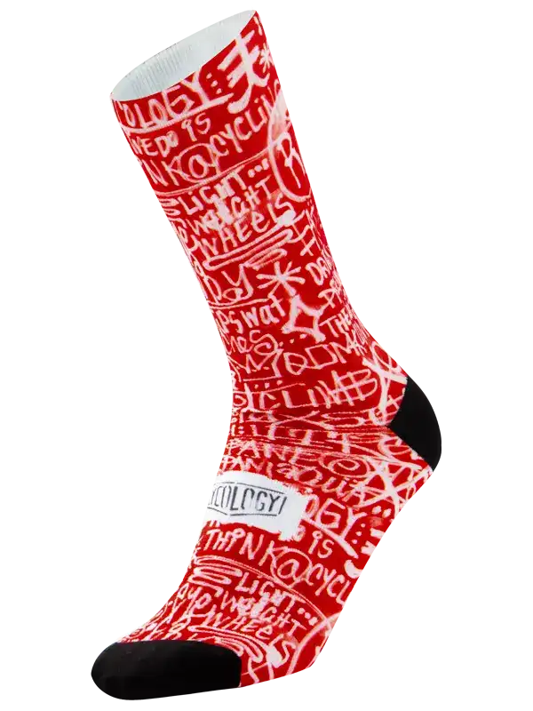 A single crew cycling sock with a red and white graffiti-style pattern featuring the word 'CYCOLOGY' on the side, finished with black toe and heel sections, shown on a plain white background.