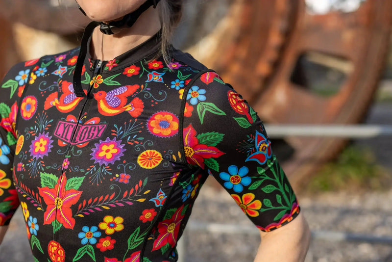 Women's cycling jersey with vibrant floral and bird print, short sleeves, black base, perfect for road biking.
