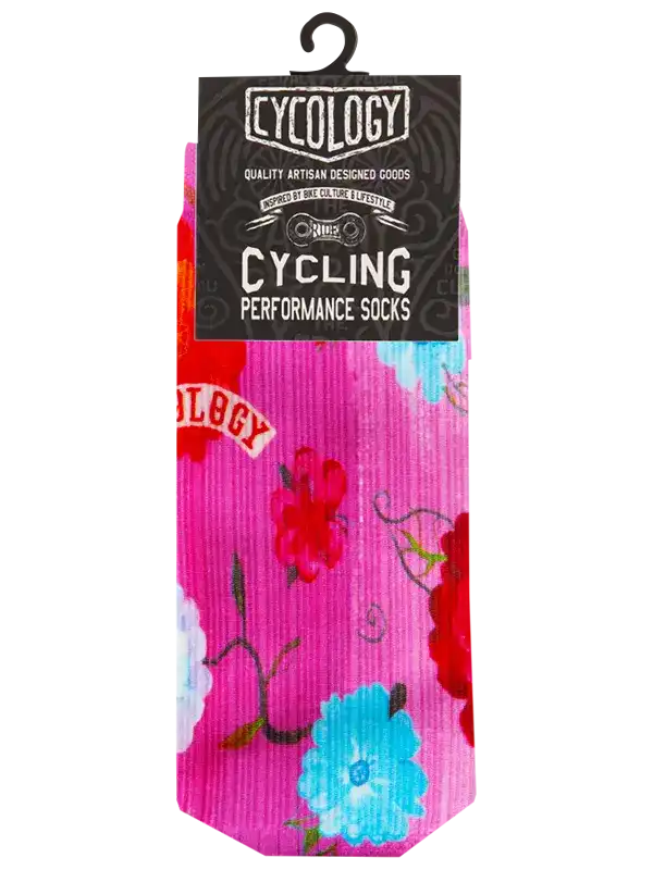 A pair of pink cycling performance socks with a colorful floral pattern, hanging from a black hanger with a black 'Cycology' branded retail card.