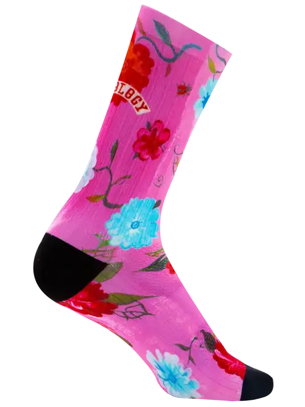A single crew cycling sock with a bright pink background, featuring a large red flower, a light blue and white flower, and the word 'CYCOLOGY' in a red banner near the upper calf. The sock has a black toe and heel, and is shown on a plain white background.