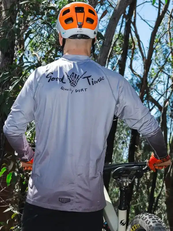 Men's cycling jersey with 'Good Times Quality Dirt' graphic, worn on trail ride with orange helmet