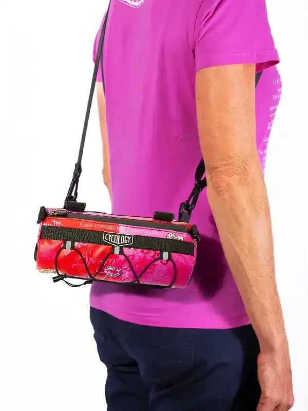 Cycology pink cycling bag with black straps worn crossbody, ideal for bike rides and outdoor adventures.