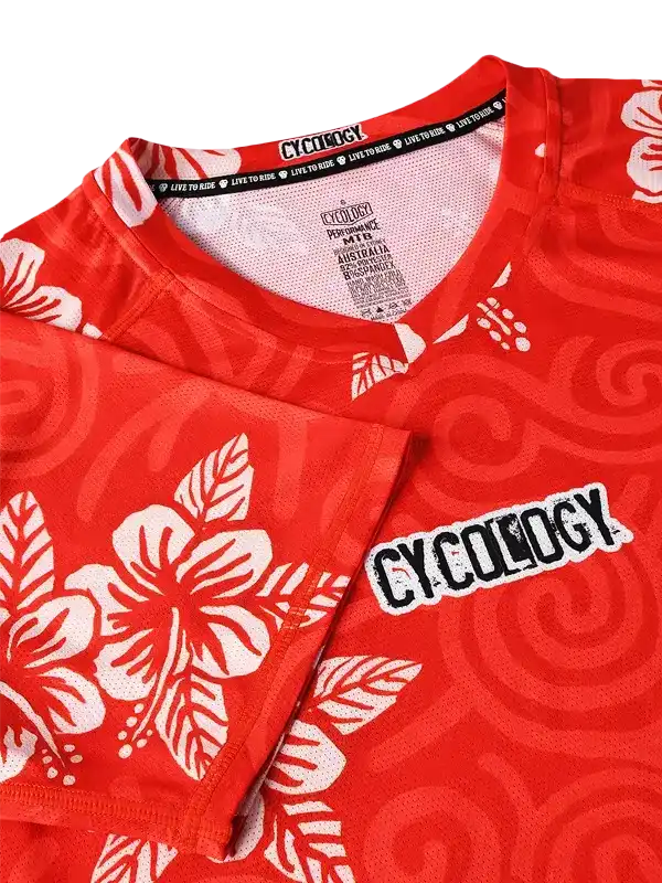 Red cycling jersey with white hibiscus flowers and swirl patterns, featuring 'CYCOLOGY' branding