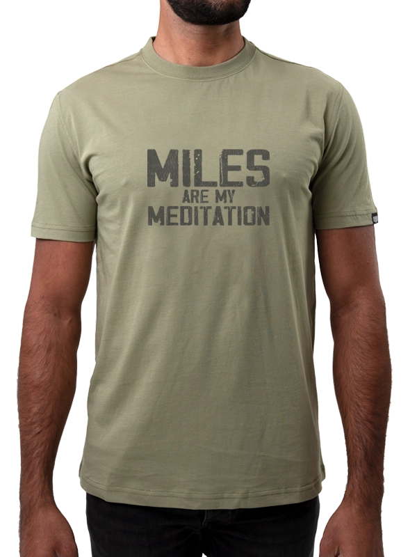 Person wearing a green t-shirt with 'MILES ARE MY MEDITATION' text on a white background
