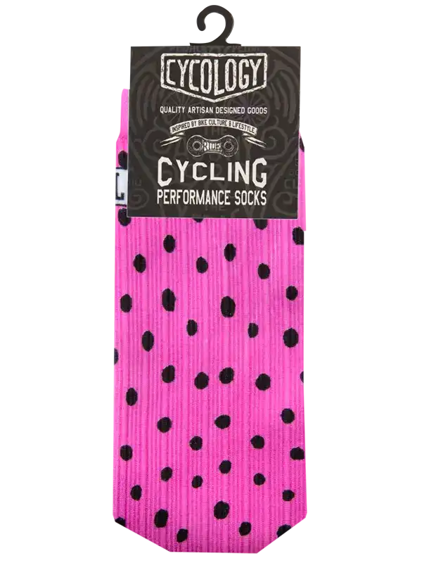 A pair of bright pink cycling socks with black polka dots, packaged on a black cardboard hanger labeled 'Cycology Cycling Performance Socks' against a plain white background.
