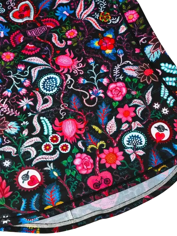 Vibrant floral cycling shorts with bold pink, blue, and red patterns on black fabric, featuring heart and bike motifs.