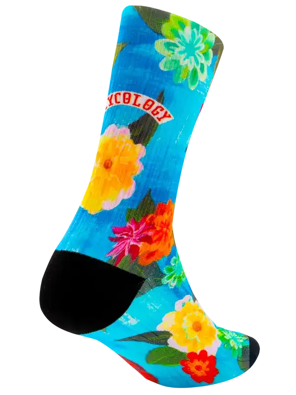 A single crew cycling sock with a bright blue background, featuring a colorful floral print in yellow, pink, red, and green, with a black toe and heel and the word 'CYCOLOGY' printed in red on a white banner.