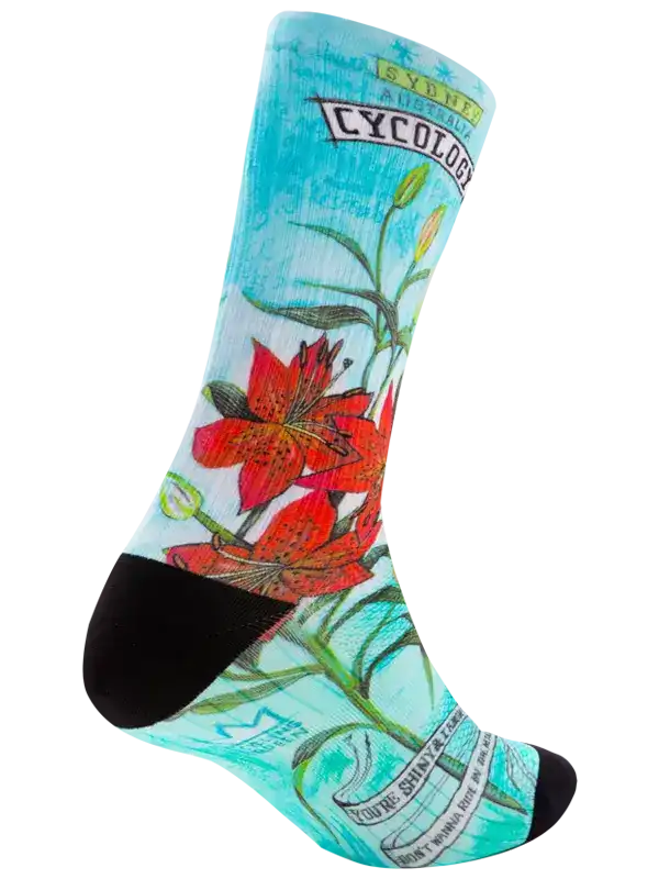 A single crew sock with a light blue background featuring a red lily flower illustration, green stems, and text including 'CYCOLOGY