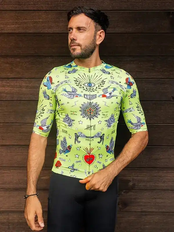 Men's neon green cycling jersey with tattoo-style bird and heart print, paired with black bib shorts