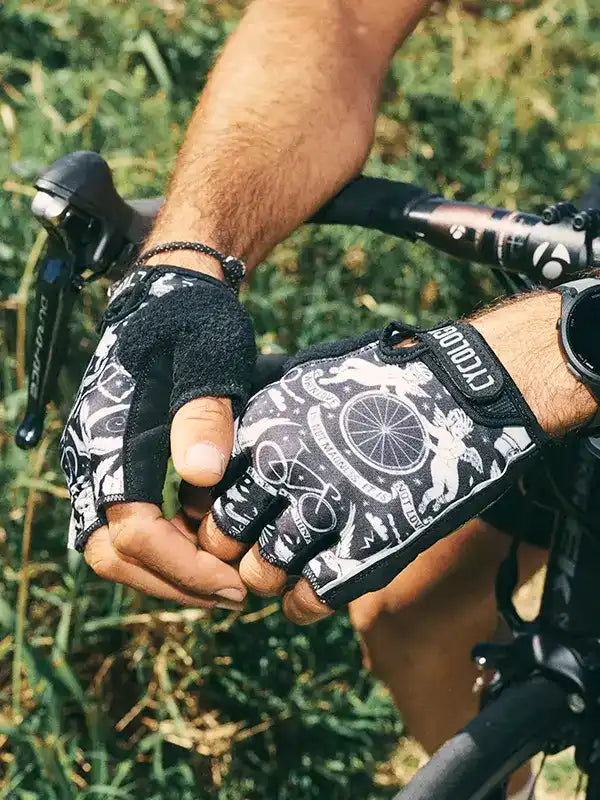 Cycling gloves with bike graphic design, worn on hands gripping handlebars outdoors