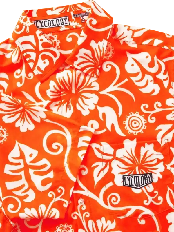 Vibrant orange cycling shirt with white floral and gear print, featuring Cycology branding on collar and chest.