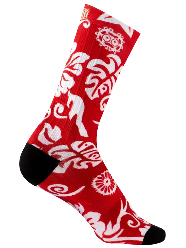 A single crew cycling sock with a vibrant red background and a white floral and scroll pattern, featuring solid black heels, toes, and cuffs, shown against a plain white background.