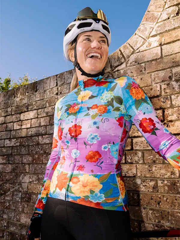 Colorful women's long sleeve  cycling jersey with floral design and 'Cycology' branding on a pink and blue background