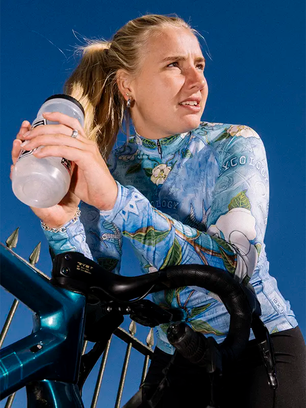 Cyclist on bike wearing Blue women's long sleeve cycling jersey with floral and bird design 
