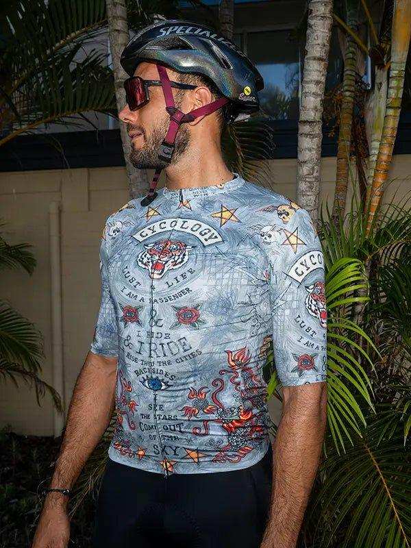 Men's cycling jersey with tattoo-style graphics, worn with helmet and sunglasses outdoors